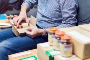 Man inserting pill bottles with custom labelling into a shipping box.